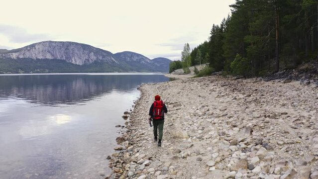 guy traveler walks along the shore with a backpack along a beautiful lake. Aerial shot
