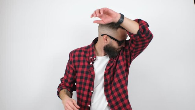 Young bearded hipster guy sweating a lot, smells bad. A man is worried and shows a problem with sweating, sniffing his armpit. Bad smell, excessive sweating concept.