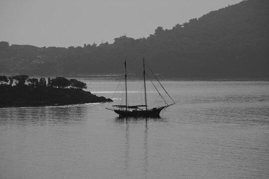 Black and white image of a gulet with calm sea and mountain at back ground.