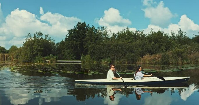 Young Couple In Canoe Paddling In Sync