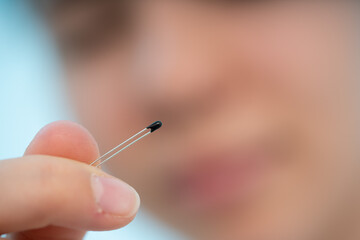 young woman holds a thermistor in her hands a semiconductor element for measuring temperature