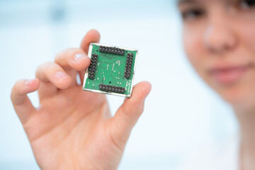 girl holds in her hands an electronic module resistant to radiation for use in military equipment
