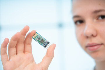 girl holds in her hands a miniature radio transmitter module for exchanging digital information in...