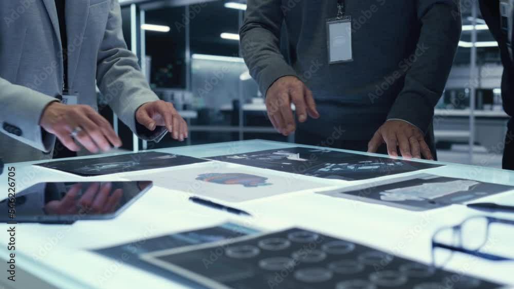 Poster close up footage with a diverse anonymous team of industrial engineers gathered around table at a fa