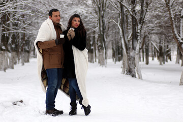 A young couple walk in a winter park