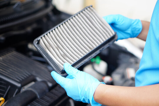 Mechanic's hands hold dusty and dirty air filter pad of car. Concept: checking and maintenance machine, car engine.                     