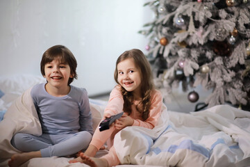 A family with children having fun on the bed under the covers during the Christmas holidays.