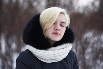 Young beautiful girl on a walk in winter park