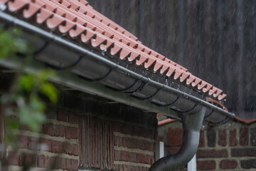 Rain dripping from the roof of a farmhouse into the gutter