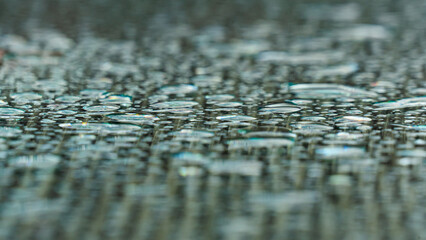 Fototapeta premium Close-up of raindrops on the glass surface of a garden table photographed with an extremely shallow focus