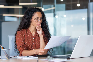 Successful satisfied and happy business woman working inside modern office, hispanic woman in glasses and shirt using laptop at work, - obrazy, fototapety, plakaty