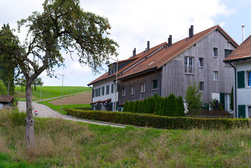 Fototapeta na wymiar Scenic view of rural Ettenhausen hamlet with old farm houses on a cloudy late summer day. Photo taken September 1st, 2022, Ettenhausen, Switzerland.