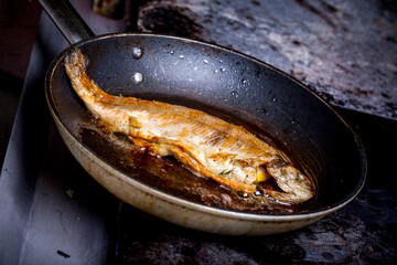 Fish being fried in a frying pan in a restaurant