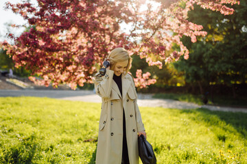 Caucasian blonde woman wearind trench smile happily on sunny spring day outside walking in park