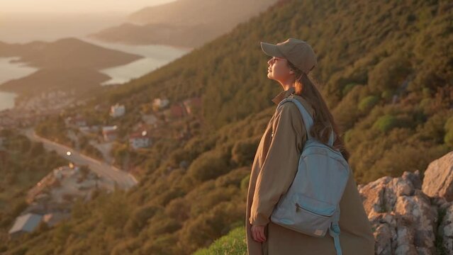 A young woman stands on a viewpoint and admires the view of a coastal city in Turkey. The tourist destination is Kash, Turkey.