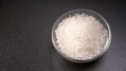 Bowl and spoon with sugar on wooden background.