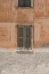 Pink coral facade wall and wooden window with shutters. Traditional European old town building. Abstract Italian architecture design