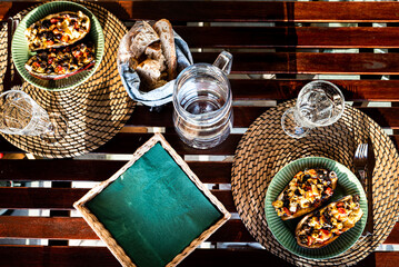 Rustic wooden table with 2 green plates of stuffed aubergines or eggplants. Nutritious aubergine or eggplant stuffed with olives, tomato and onions is a rich dish that provides energy and calories