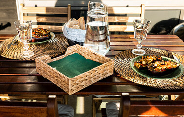 Meal with stuffed aubergines and homemade bread outdoor in the sunshine. Delicious dish on rustic wooden table outside in the sun light with filled eggplants and handmade bread as lunch or dinner