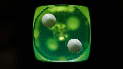A green dice at the number two on a black background.