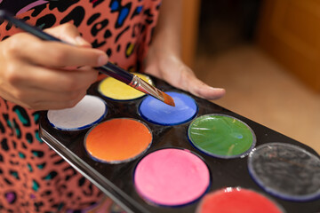 Naklejka premium Close up view of an artist's palette during a skin painting session at her client's home