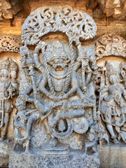 Obraz premium Stunning bas-relief of Ugra Narasimha, an avatar of Vishnu, adorns the Hoysaleswara Temple in Halebidu, India. The carving shows the fierce deity subduing demon king Hiranyakashipu with multiple arms.