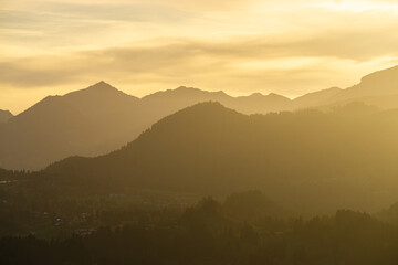 Spectacular view of mountain ranges silhouettes with yellow sunlight. Sunset in Allgau, Germany, Alps.