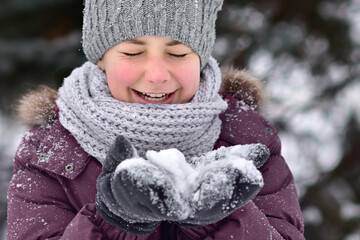 The girl plays with snow and laughs merrily. Winter fun