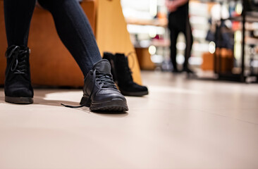 Naklejka premium Woman trying new black shoes sitting in a shop