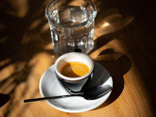 Espresso in a black cup served with glass of water. Shallow depth of field