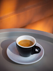 Espresso on a gray table near a red wall