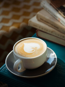 Cappuccino on the green table next to the books