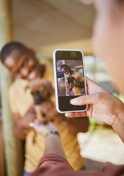 Phone picture, dog and woman hand showing man and new pet outdoor with happiness. Black man, puppy and black woman together with couple bonding hug using mobile technology and camera with a smile