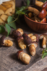 Pile of Imleria Badia or Boletus badius mushrooms commonly known as the bay bolete with canned mushroom in glass jar on vintage wooden background..