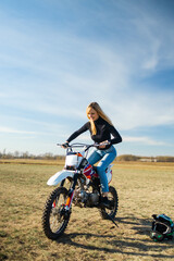 Fototapeta na wymiar Attractive blonde girl on motocross. Sporty woman biker at motobike. Countryside, country road. sunset, female motorcycle rider, motorbike rider travel the world, girl resting, freedom lifestyle