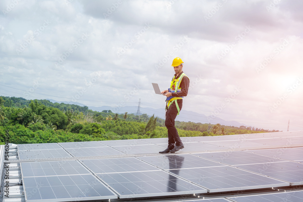 Poster engineer working and maintenance with solar batteries near solar panels at sunny day on roof structu