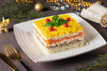 Festive puff salad Mimosa with canned fish, potatoes, cheese, carrots and eggs on brown background