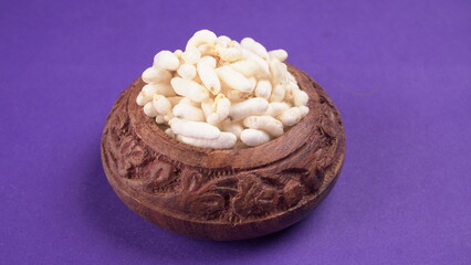 puffed rice inside wooden bowl with puffed rice resting on white background with top view