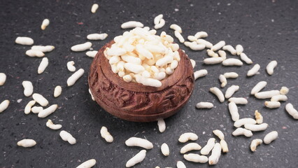 puffed rice inside wooden bowl with puffed rice resting on white background with top view