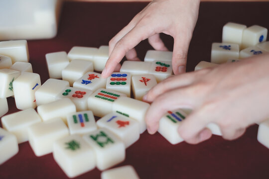 Hands arranging, playing Mahjong game. Concept of chinese leisure games traditional, family activity, Hongkong board game, chinese new year fmily time entertainment. Lucky game.