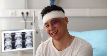 Male patient with bandaged head and bruised face acting crazy in hospital ward - obrazy, fototapety, plakaty