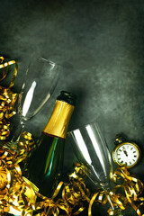 Happy New Year. Champagne bottle with two glasses,golden streamers and antique clock with copy space. New Years Eve celebration concept background