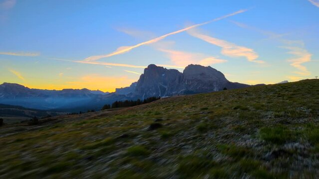 Mountains, forest and grass fields with wooden cabins filmed at Alpe di Siusi in Alps, Italian Dolomites filmed in vibrant colors at sunrise. Filmed with a drone with forward movement, wide view