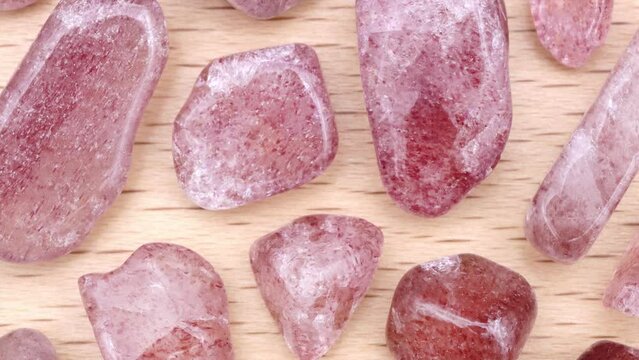 Strawberry quartz rare jewel stones texture on light varnished wood background. Moving right seamless loop backdrop.