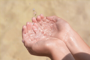 Pouring water into kid`s hands outdoors, closeup