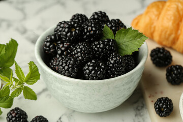Bowl of fresh ripe blackberries on white marble table, closeup