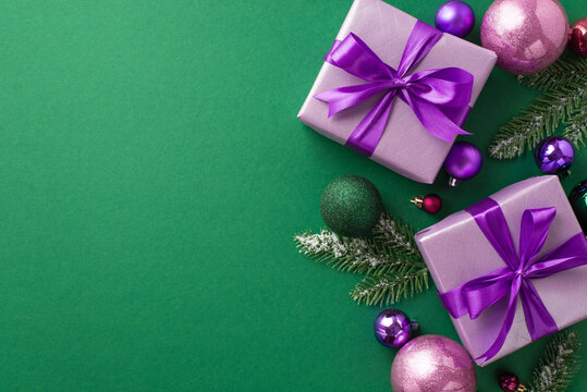 New Year concept. Top view photo of lilac gift boxes with violet ribbon bows pink purple green baubles balls and pine branches in hoarfrost on isolated green background with blank space