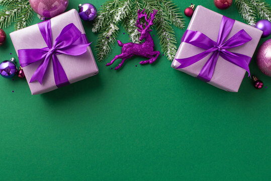 New Year concept. Top view photo of purple gift boxes with violet ribbon bows pink lilac baubles deer ornament fir branches in snow and confetti on isolated green background with blank space