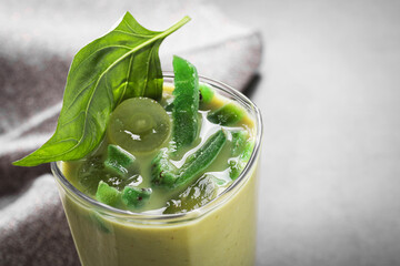 Glass of delicious smoothie with grape, candied kiwi and basil on grey table, closeup. Space for text