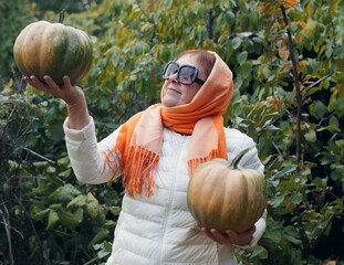 An elderly woman holds a grown pumpkin. Healthy natural vegetarian food.